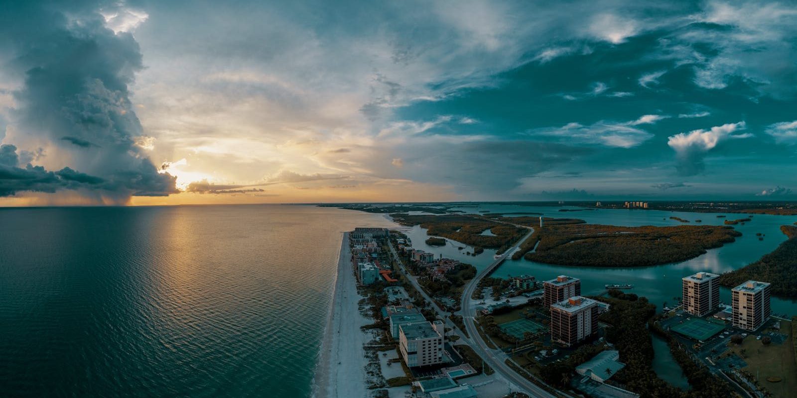 Stunning aerial view of Bonita Springs coastline during sunset with dramatic clouds.