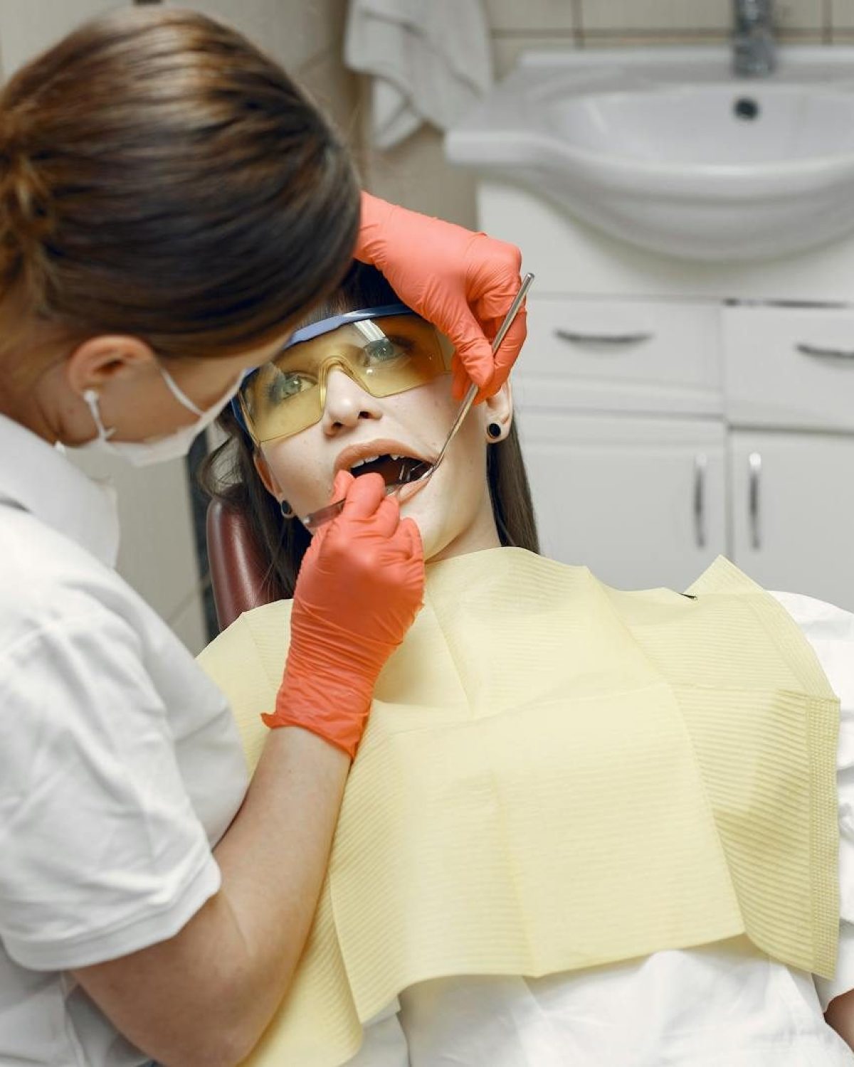 Professional dentist examines patient in a dental clinic with safety gear.