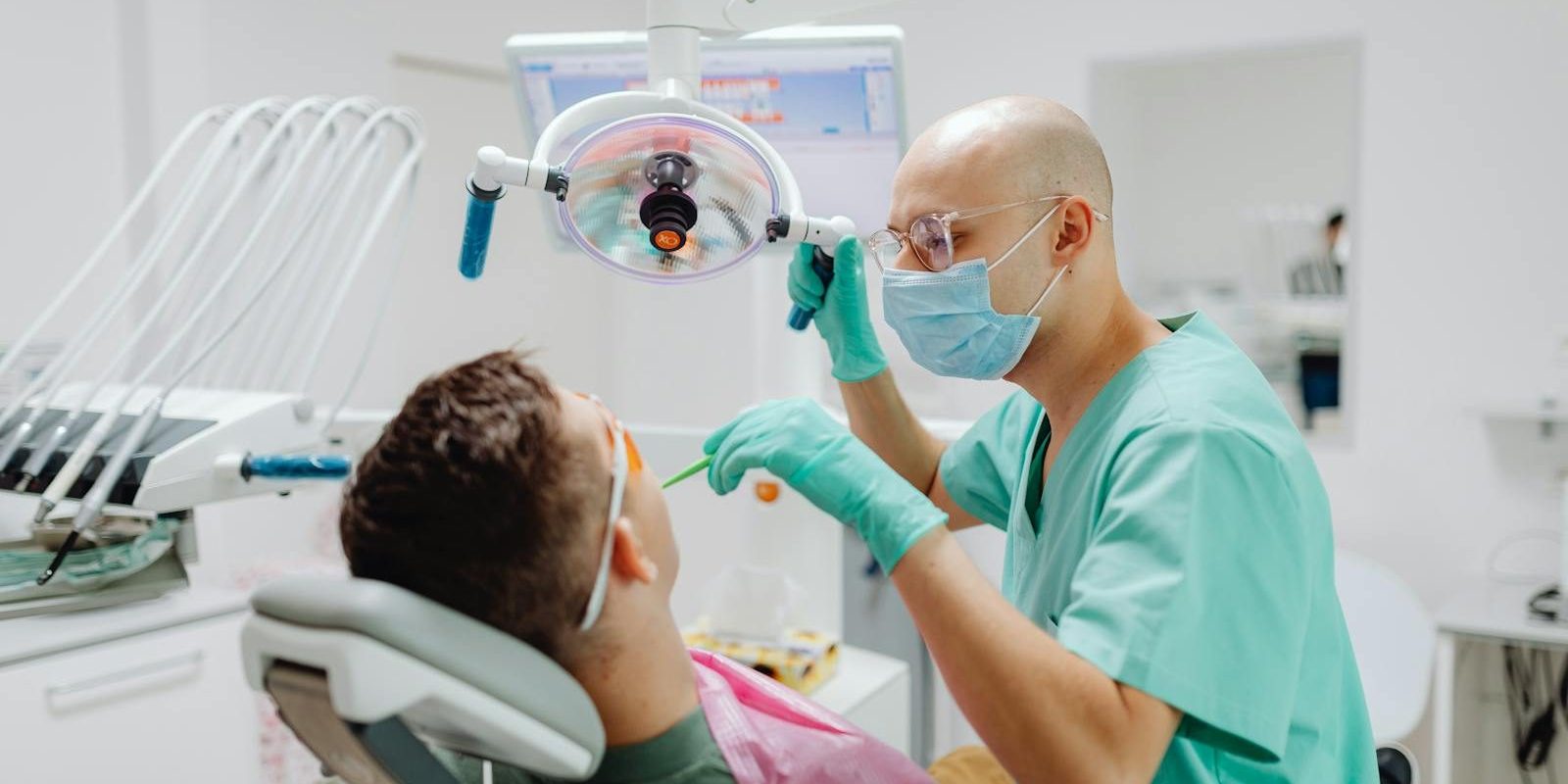 A dentist in a medical clinic conducts a dental check-up on a seated patient.