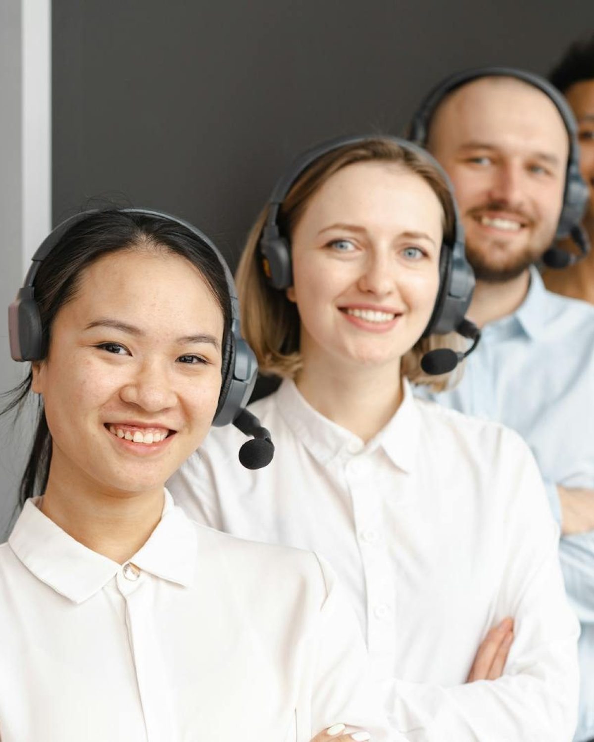 Smiling customer service team wearing headsets in an office setting, ready to assist clients.